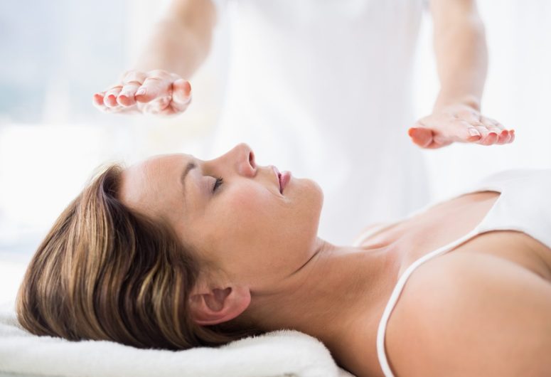 Midsection of therapist performing reiki treatment on woman