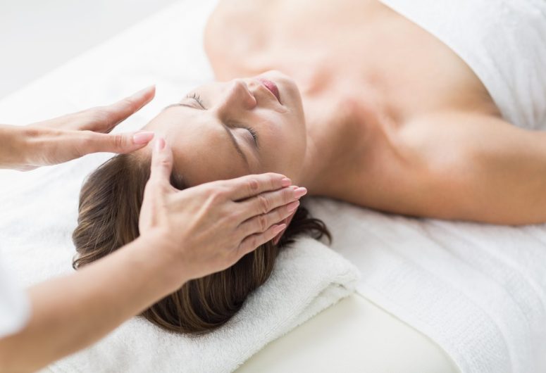 Cropped hands of therapist performing reiki on woman